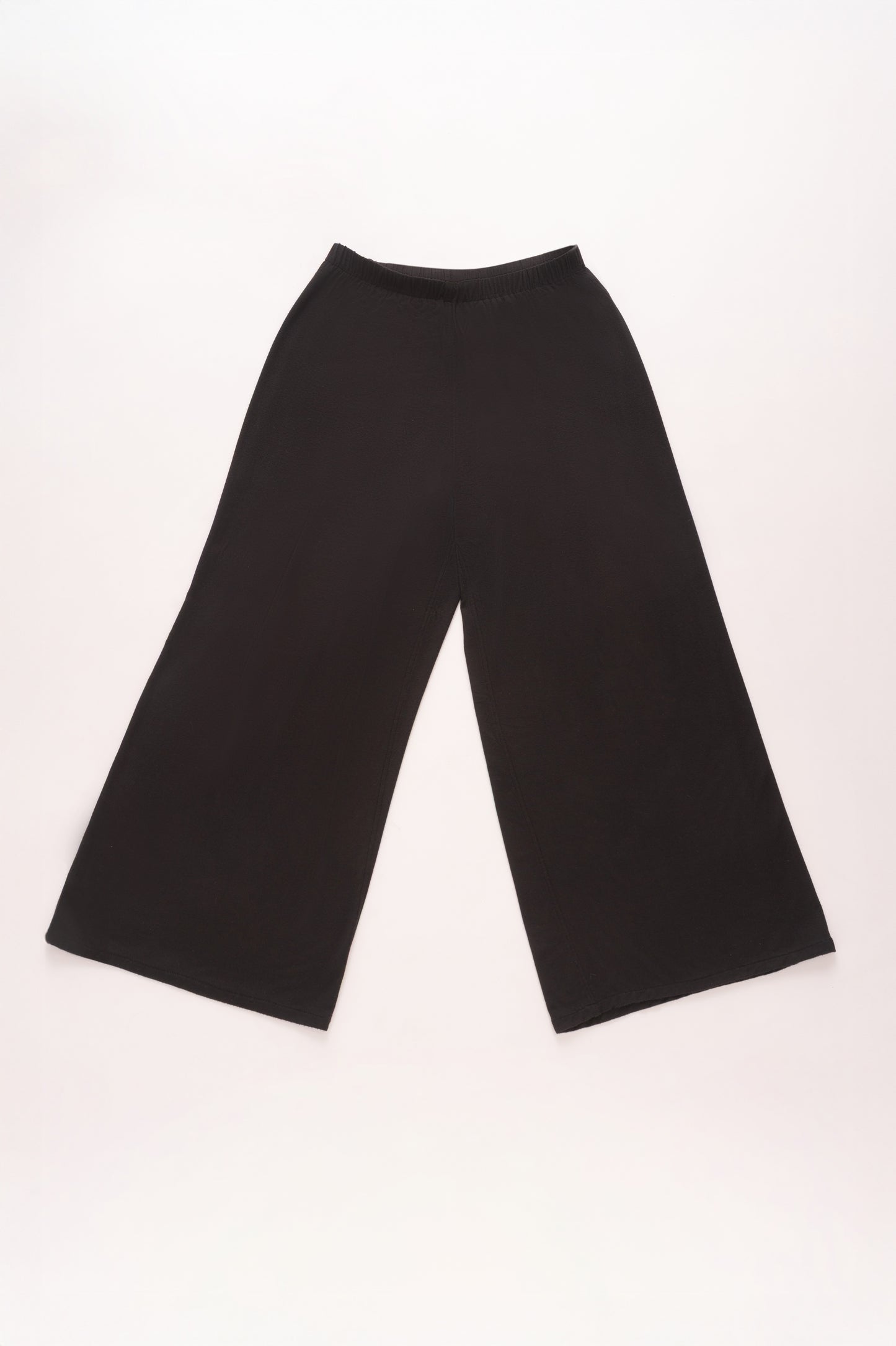 Flat lay of black wide-leg pants with a relaxed silhouette and soft elastic waistband, displayed against a light background.