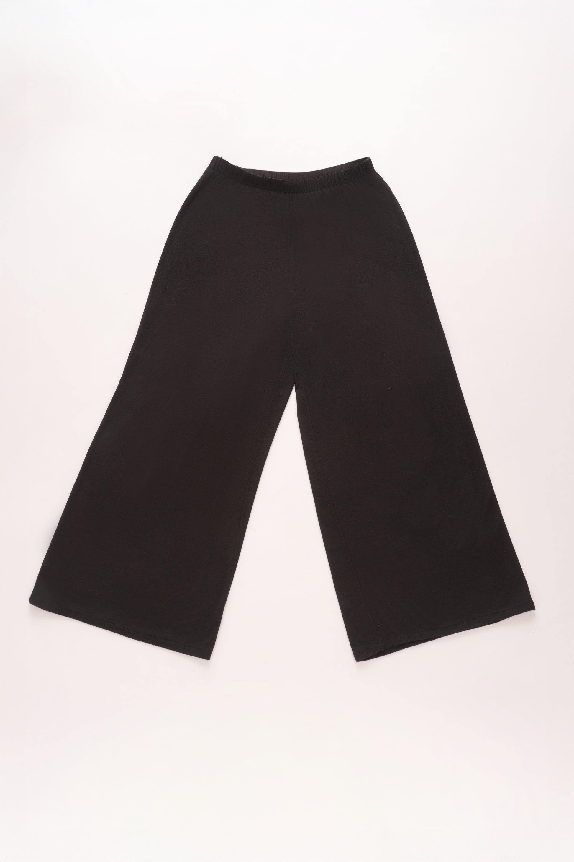 Flat lay of black wide-leg pants with a relaxed silhouette and soft elastic waistband, displayed against a light background.